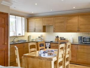 a kitchen with wooden cabinets and a wooden table and chairs at Waren View in Warenford