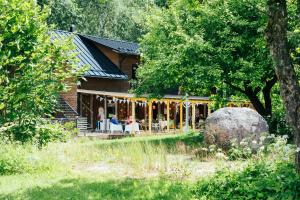 a log home with a porch and a large rock at Suur Muna Apple Garden Tiny Houses in Haanja