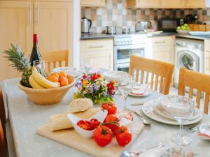 a table with a plate of fruit and a bottle of wine at Cob Cottage in Rhossili