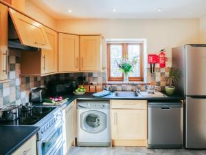 a kitchen with a washing machine and a sink at Cob Cottage in Rhossili