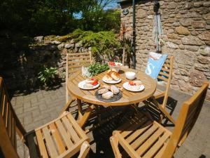 a wooden table with food on it on a patio at Cob Cottage in Rhossili