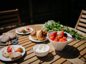 a table with plates of food and a bowl of strawberries at Cob Cottage in Rhossili +1 photo