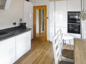 a kitchen with white cabinets and a wooden floor at Briardene Cottage in Whitestone