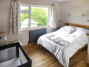 a bedroom with a white bed and a window at Briardene Cottage in Whitestone +8 photos