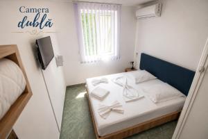 a bedroom with a bed with white sheets and a tv at Hotel Proton in Neptun