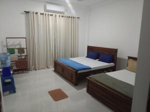 a bedroom with two beds and a chair in it at Bosadi Apartment katunayaka in Katunayaka