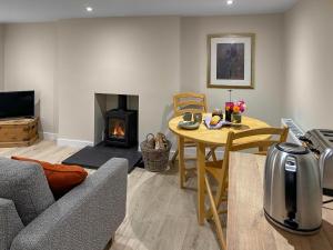 a living room with a table and a fireplace at Wagglehead Cottage in Aboyne