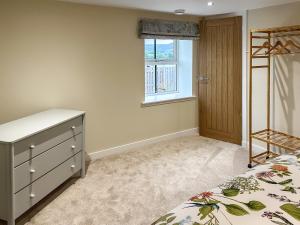 a bedroom with a bed and a dresser and a window at Wagglehead Cottage in Aboyne +11 photos