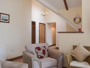 a living room with a chair and a couch at Brynymor Cottage in Llangennith