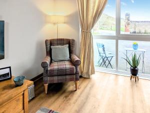 a living room with a chair and a window at Saddlers Cottage in Melrose