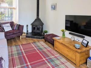 a living room with a tv and a fireplace at Saddlers Cottage in Melrose