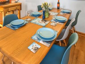 a wooden table with blue plates and glasses on it at Saddlers Cottage in Melrose