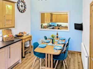 a dining room with a wooden table and blue chairs at Saddlers Cottage in Melrose