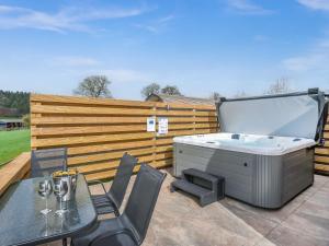 a hot tub on a patio with a table and chairs at Squirrels Retreat - Uk46127 in Nesscliffe