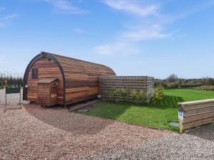 a large wooden shed with a grass yard at Squirrels Retreat - Uk46127 in Nesscliffe