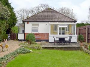 a small white house with a table in a yard at Oak Lodge in Longham