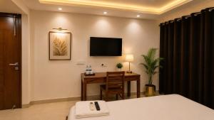 a hotel room with a desk and a television on the wall at Lime Tree Hotel Golf Course Extension Nearby Grand Hyatt Gurgaon in Gurgaon