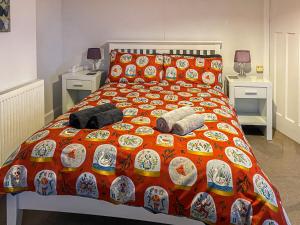 a bed with an orange comforter and pillows on it at Beacon Cottage in Ivybridge +17 photos