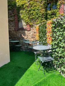 a patio with tables and chairs and a wall with flowers at Voyageur - Vidéoprojecteur - Terrasse - 5min gare in Ploumagoar