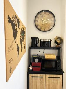a room with a microwave and a clock on a wall at Voyageur - Vidéoprojecteur - Terrasse - 5min gare in Ploumagoar