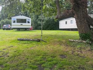 a white trailer in a yard next to a tree at Kingfisher - Uk52120 in Hevingham