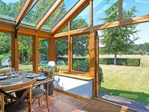 a conservatory with a table and chairs and glass windows at The Granary - Uk52147 in Brundall +20 photos