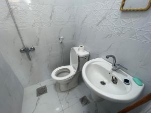 a white bathroom with a toilet and a sink at Pizza Street Hostel in Aqaba +58 photos