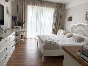 a white bedroom with a white bed and a desk at Blaxy del Mar Studio Olimp in Olimp +14 photos