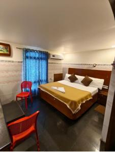 a bedroom with a bed and a red chair at HoTEL SVR ELITE in Vijayawāda +21 photos