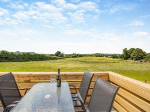 a table and chairs on a deck with a view of a field at Rabbits Rest - Uk46128 in Nesscliffe