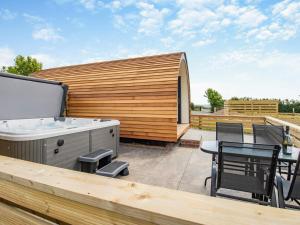 a deck with a hot tub and a table and chairs at Rabbits Rest - Uk46128 in Nesscliffe +4 photos