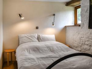 a bedroom with a bed with white sheets and two lights at Swallows Barn in Liskeard