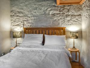 a bed with white sheets and two lamps in a bedroom at Swallows Barn in Liskeard