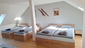 two beds in a room with white walls and wood floors at Apartman Glacier in Tatranska Strba