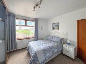 a bedroom with a bed and a window at Maple Cottage in Inverallochy