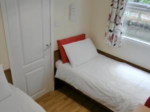 a small bedroom with a bed and a window at White Moth - Uk12697 in Stalham