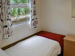 a small bedroom with a bed and a window at White Moth - Uk12697 in Stalham