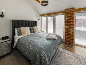 a bedroom with a large bed and a brick wall at Rose Blossom Cottage in Benniworth