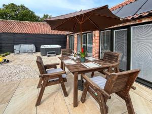 a wooden table and chairs with an umbrella on a patio at Rose Blossom Cottage in Benniworth
