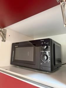 a black microwave on a shelf in a kitchen at FeWo Mangfall in Bruckmühl