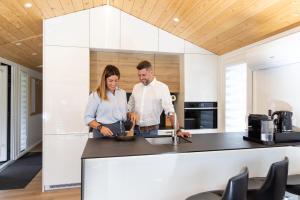 a man and woman preparing food in a kitchen at Chalet Stuhleckblick Ferienhaus mit Sauna, Panorama und Terrasse in Spital am Semmering