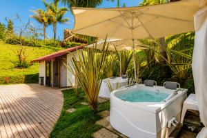 a bath tub with an umbrella next to a house at Hotel Pietrasanta Cabañas frente a la Represa Peñol Guatape in Guatapé