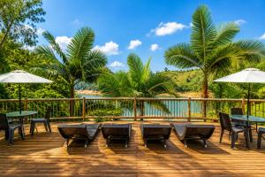 a deck with tables and chairs and umbrellas at Hotel Pietrasanta Cabañas frente a la Represa Peñol Guatape in Guatapé