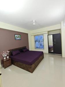a bedroom with a large purple bed and a window at Aura Vista in Bhopal