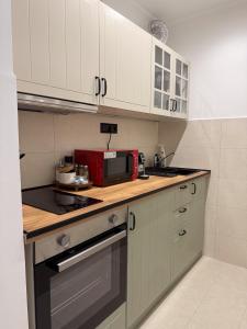 a kitchen with white cabinets and a red microwave at Radnóti Apartman Győr in Győr +9 photos