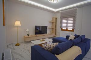 ein Wohnzimmer mit einer blauen Couch und einem Fernseher in der Unterkunft The Archanes Ruby in Archanes