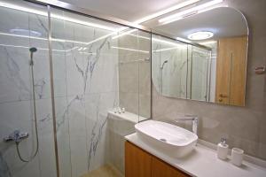 ein Badezimmer mit Waschbecken und Dusche mit Spiegel in der Unterkunft The Archanes Ruby in Archanes + 20 Fotos