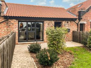 a brick house with glass doors and a fence at Valentines Cottage - Uk48509 in Kirk Hammerton +3 photos