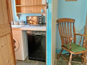 a kitchen with a chair and a microwave and a dishwasher at Downhouse in Delabole