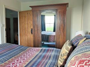 a bedroom with two beds and a large mirror at Downhouse in Delabole